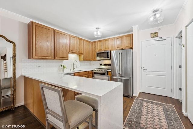 kitchen featuring premium appliances, a peninsula, light countertops, a kitchen bar, and a sink