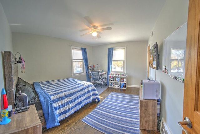 bedroom featuring a ceiling fan, visible vents, dark wood finished floors, and baseboards