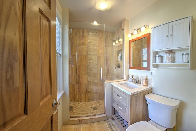 bathroom featuring toilet, a stall shower, and vanity