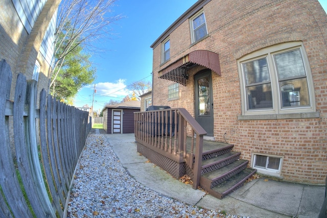 property entrance with brick siding, fence, and visible vents