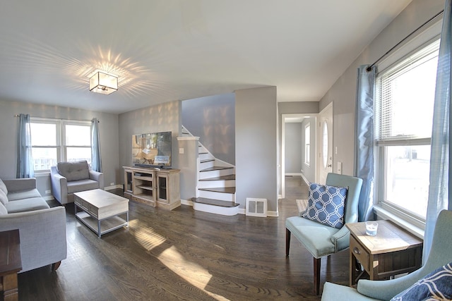 living room featuring dark wood-type flooring, visible vents, stairway, and baseboards