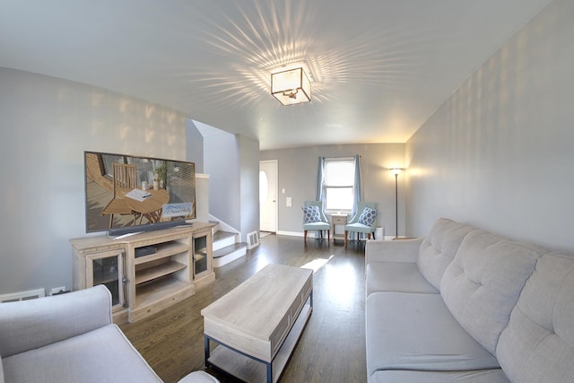 living room featuring dark wood-style floors, stairs, visible vents, and baseboards