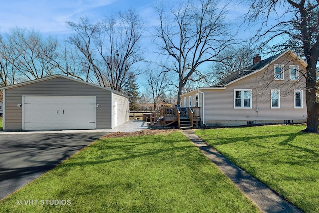 exterior space featuring a yard, a wooden deck, a detached garage, and an outdoor structure