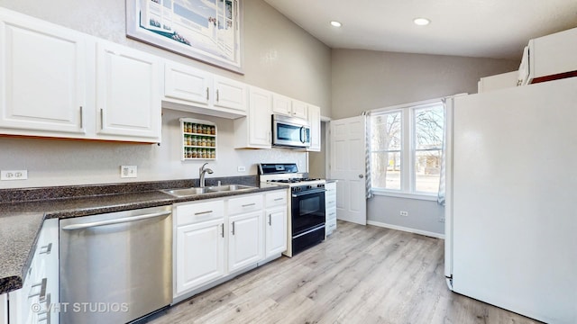 kitchen featuring lofted ceiling, white cabinets, stainless steel appliances, and a sink