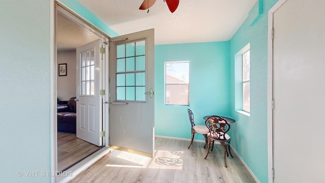 doorway to outside with a textured ceiling, wood finished floors, a ceiling fan, and baseboards