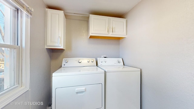 clothes washing area with a wealth of natural light, washer and dryer, and cabinet space