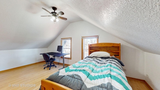 bedroom with a textured ceiling, vaulted ceiling, wood finished floors, and baseboards