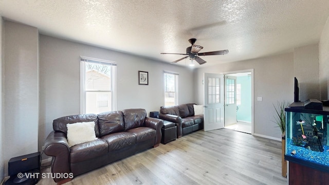 living area featuring a textured ceiling, wood finished floors, a ceiling fan, and baseboards