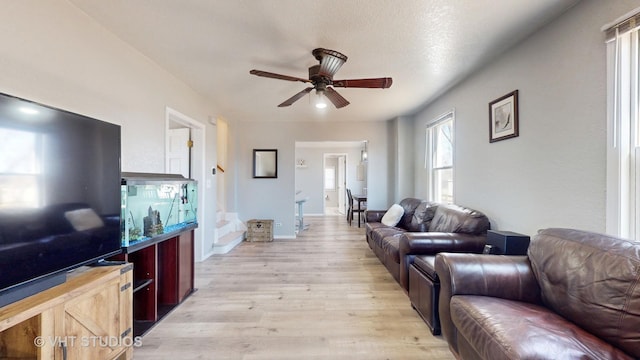 living room with baseboards, ceiling fan, and light wood finished floors