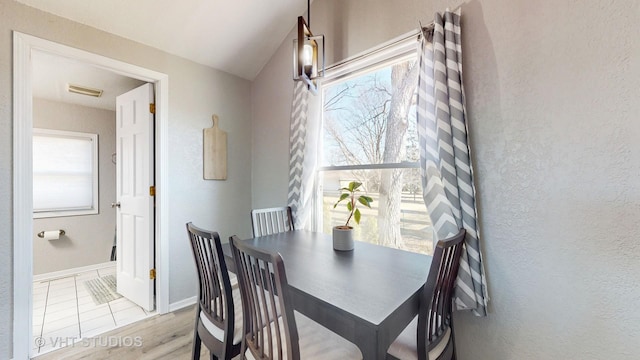 dining room with visible vents, a textured wall, baseboards, and wood finished floors