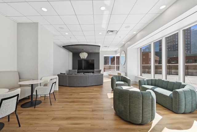 living room with a paneled ceiling, recessed lighting, visible vents, and light wood-style floors