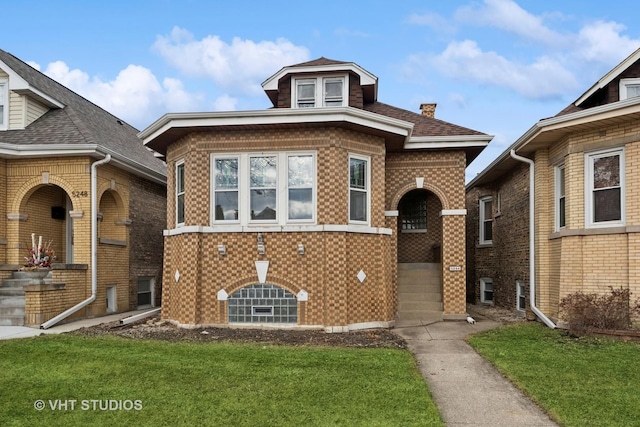 view of front of property featuring roof with shingles, a front yard, and brick siding