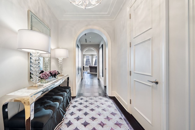 hall with baseboards, arched walkways, and dark wood-style flooring