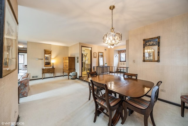 carpeted dining room featuring wallpapered walls, baseboards, visible vents, and a notable chandelier