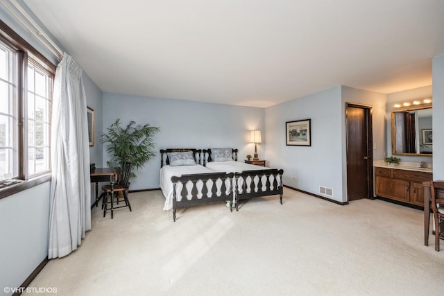 bedroom with light carpet, a sink, visible vents, and baseboards