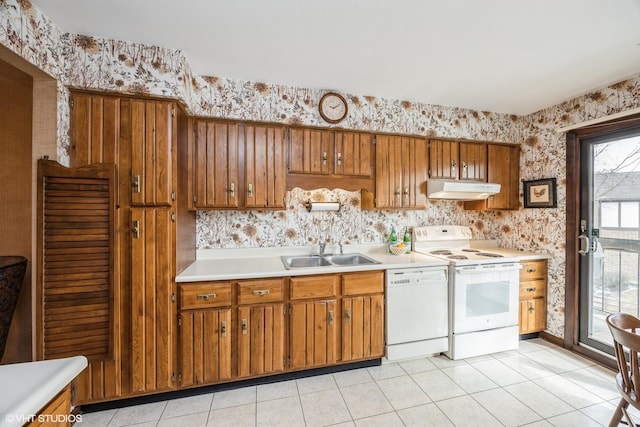 kitchen featuring wallpapered walls, white appliances, brown cabinetry, under cabinet range hood, and a sink