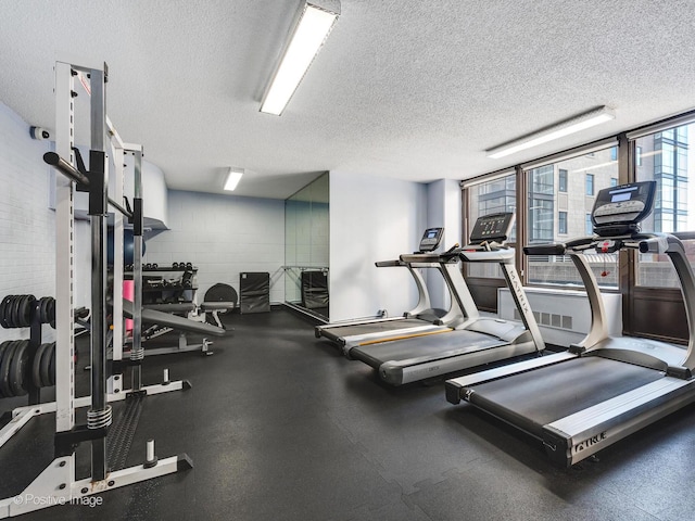 workout area featuring concrete block wall and a textured ceiling