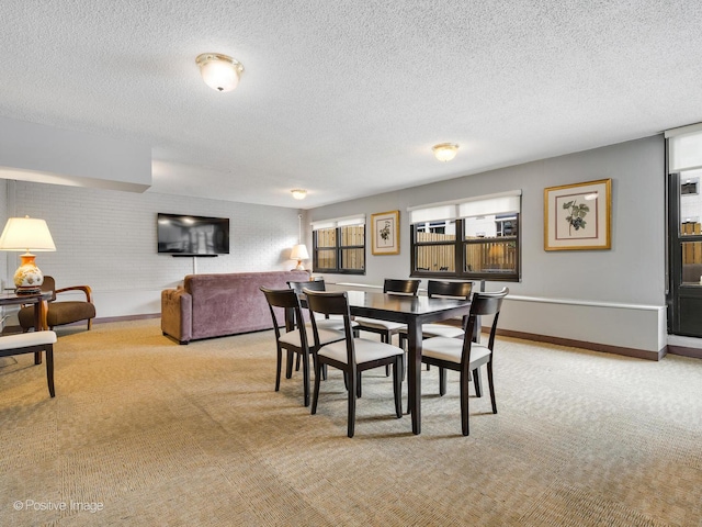 dining space featuring light colored carpet, a textured ceiling, and baseboards