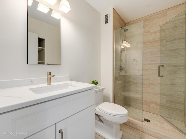 full bathroom featuring toilet, a stall shower, visible vents, and vanity