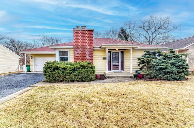 ranch-style home featuring aphalt driveway, a front yard, a chimney, and a garage