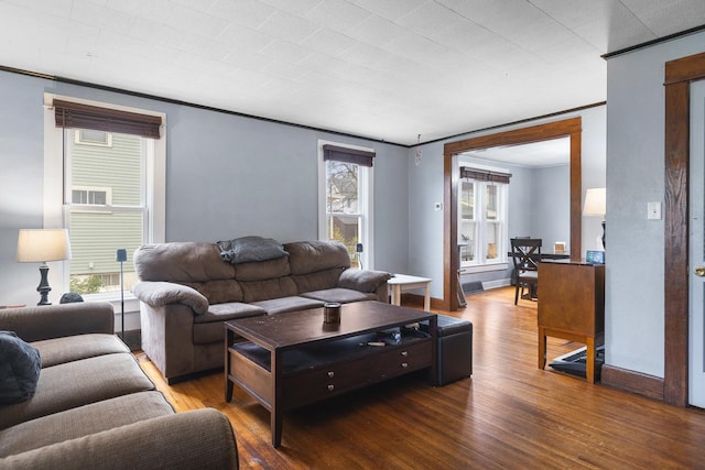 living area featuring baseboards, wood finished floors, and crown molding