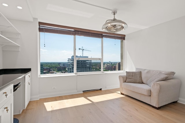 sitting room featuring light wood finished floors, baseboards, and a city view