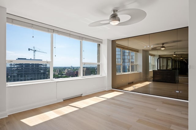 unfurnished sunroom featuring a view of city and a ceiling fan