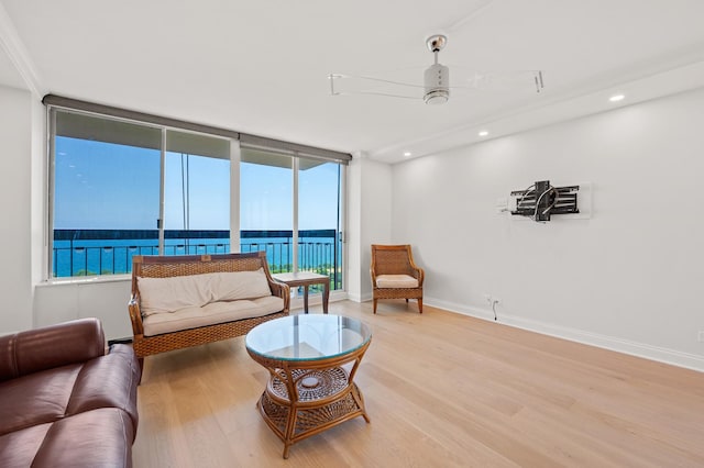 living area with recessed lighting, a water view, a ceiling fan, wood finished floors, and baseboards