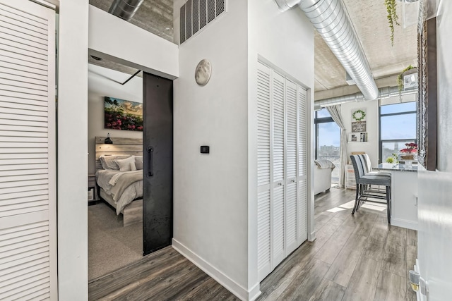 hall with wood finished floors, visible vents, and baseboards