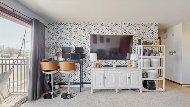 living room featuring wallpapered walls, an accent wall, baseboards, and carpet flooring