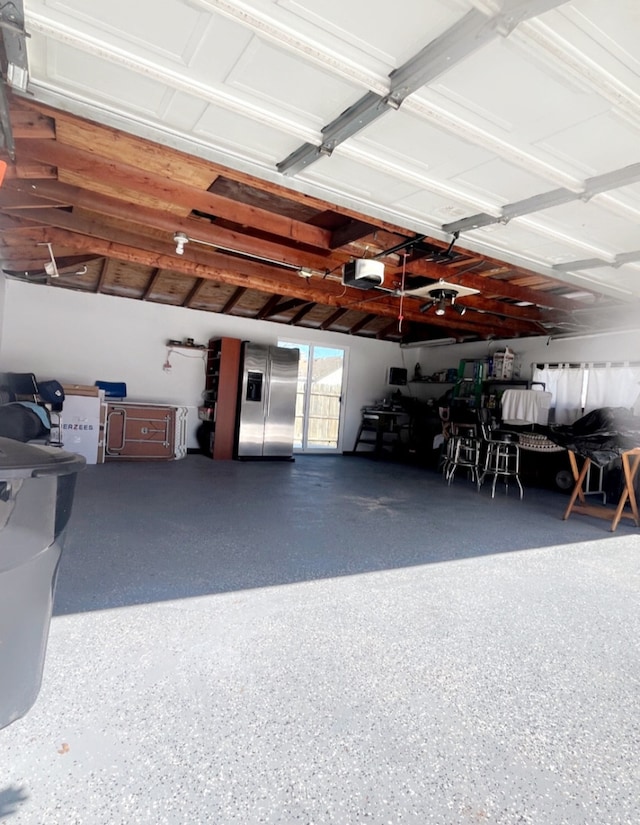 garage featuring a garage door opener and stainless steel fridge with ice dispenser