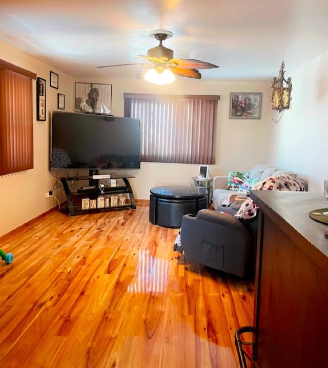 living area featuring light wood-style flooring and ceiling fan