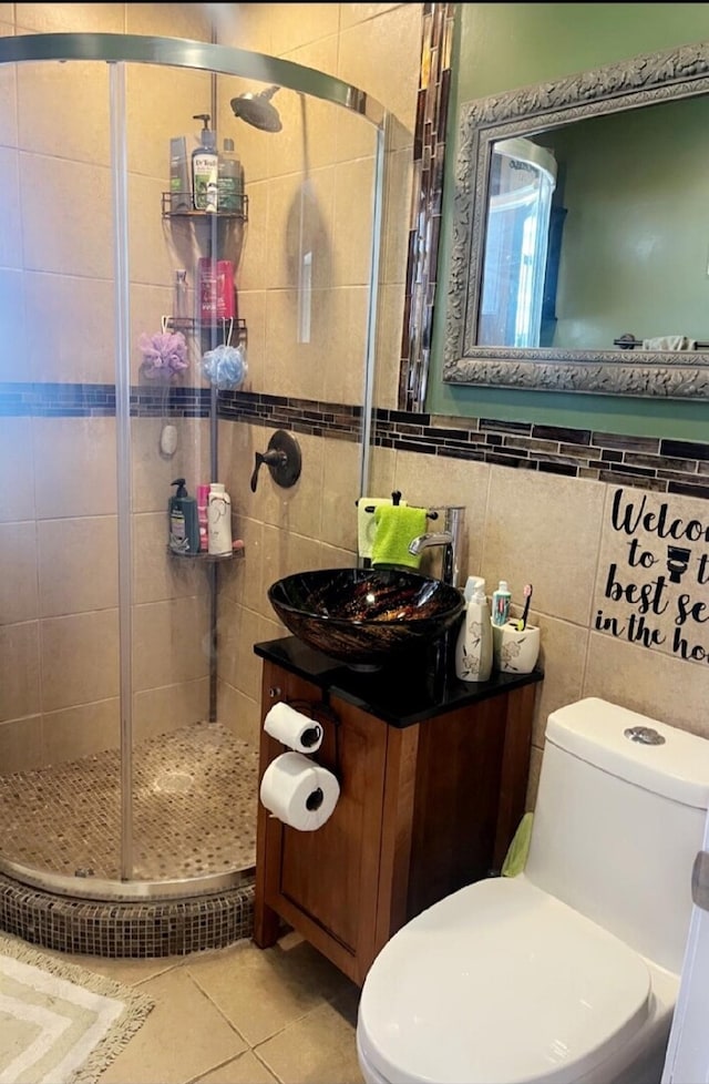 full bathroom featuring toilet, tile walls, vanity, a shower stall, and tile patterned floors