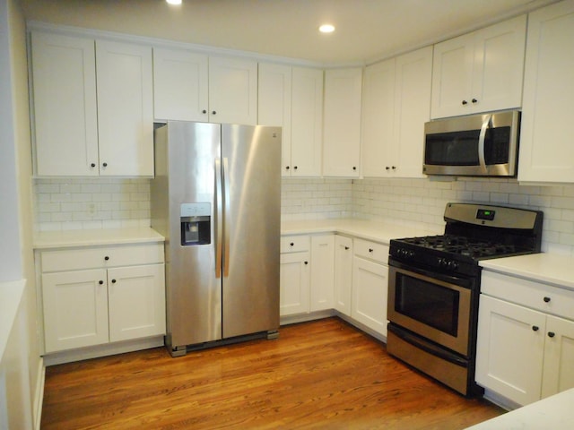 kitchen featuring stainless steel appliances, light countertops, white cabinetry, and wood finished floors