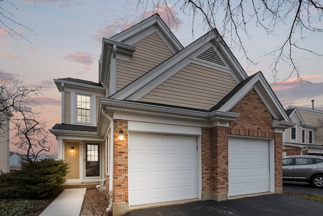 view of front of home with brick siding, driveway, and a garage