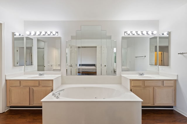 full bath featuring wood finished floors, ensuite bath, a whirlpool tub, and a sink