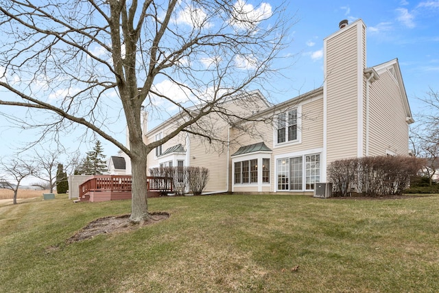 rear view of property featuring a chimney, central AC, a wooden deck, and a yard