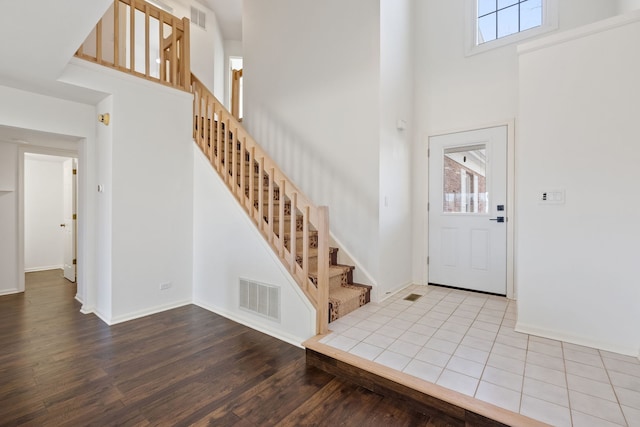 entrance foyer featuring visible vents, a high ceiling, and stairway