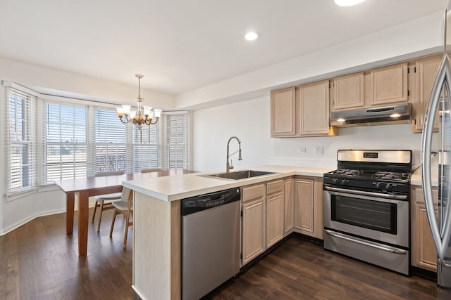 kitchen with light brown cabinets, a peninsula, a sink, stainless steel appliances, and under cabinet range hood