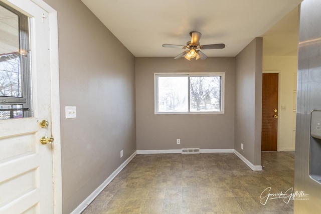 spare room featuring ceiling fan, visible vents, and baseboards