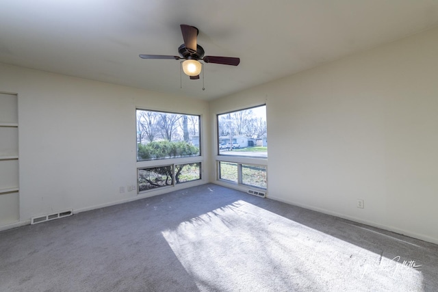 spare room featuring carpet floors, visible vents, baseboards, and a ceiling fan