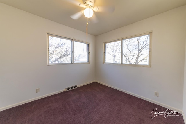 spare room featuring baseboards, visible vents, dark carpet, and a ceiling fan