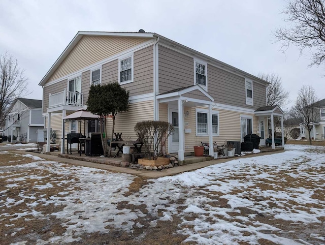 snow covered rear of property with a balcony