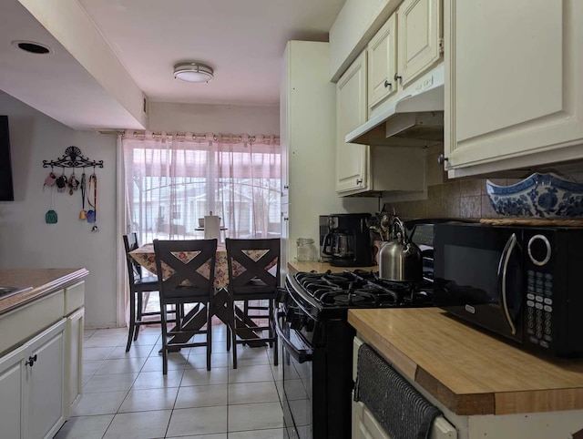 kitchen with wood counters, white cabinets, under cabinet range hood, and black appliances