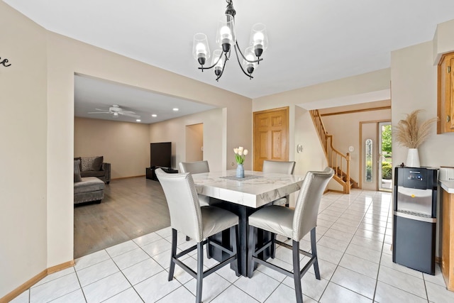 dining area with light tile patterned floors, baseboards, stairway, and ceiling fan with notable chandelier