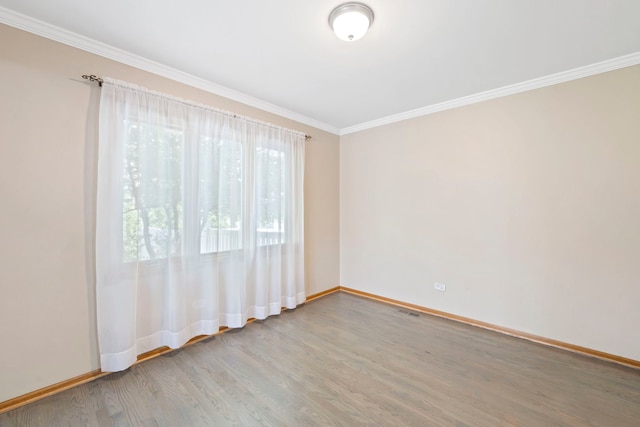 spare room with baseboards, ornamental molding, and wood finished floors