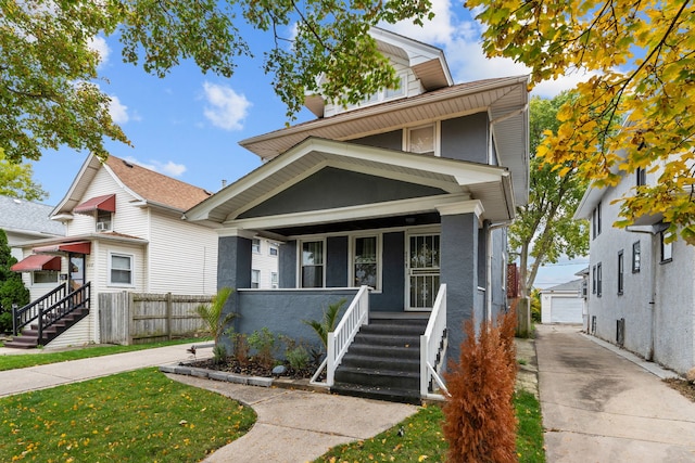 american foursquare style home with a detached garage, fence, an outdoor structure, a porch, and stucco siding