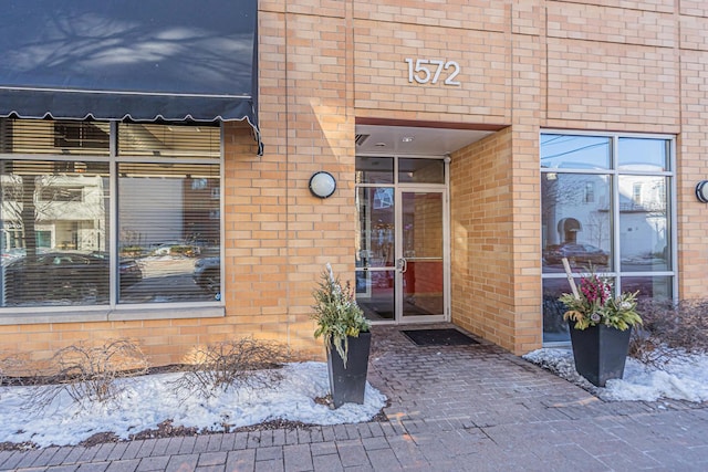 snow covered property entrance with brick siding