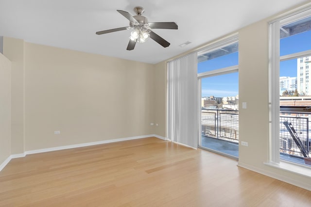 empty room with light wood finished floors, baseboards, a wealth of natural light, and a city view