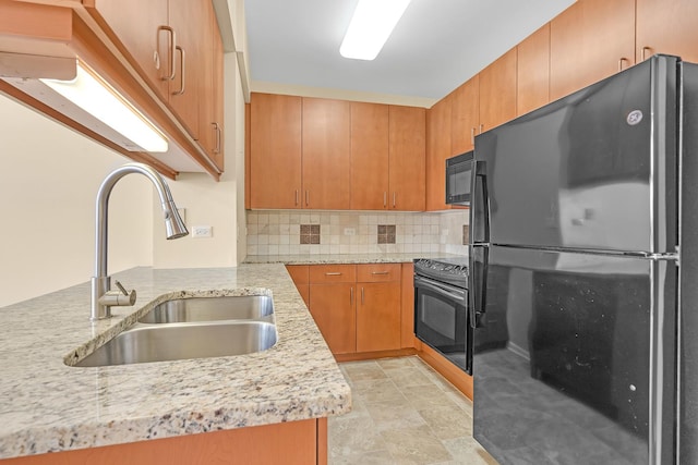 kitchen featuring black appliances, light stone counters, backsplash, and a sink